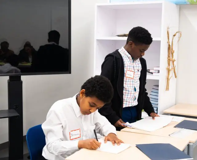 Two boys working at a desk together.